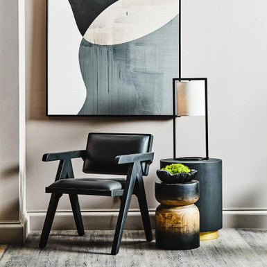 Modern interior with abstract art, black chair, and decorative plants.
