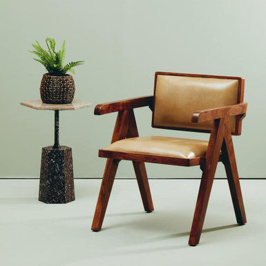 Wooden chair with brown leather seat and armrests next to a small table with a plant on a light green background