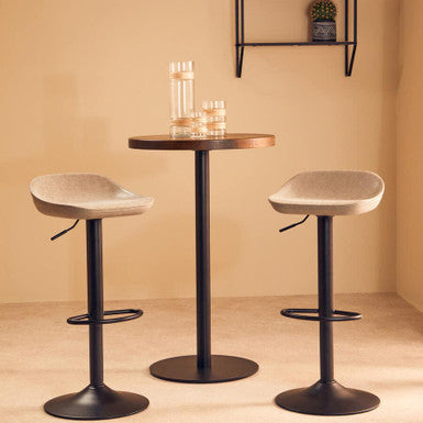 Two bar stools with a small round table against a beige wall.