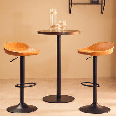 Two wooden bar stools with black metal bases in front of a small round table against a beige wall.