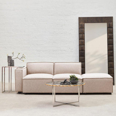 Beige sofa with a coffee table and decorative items against a light gray wall.