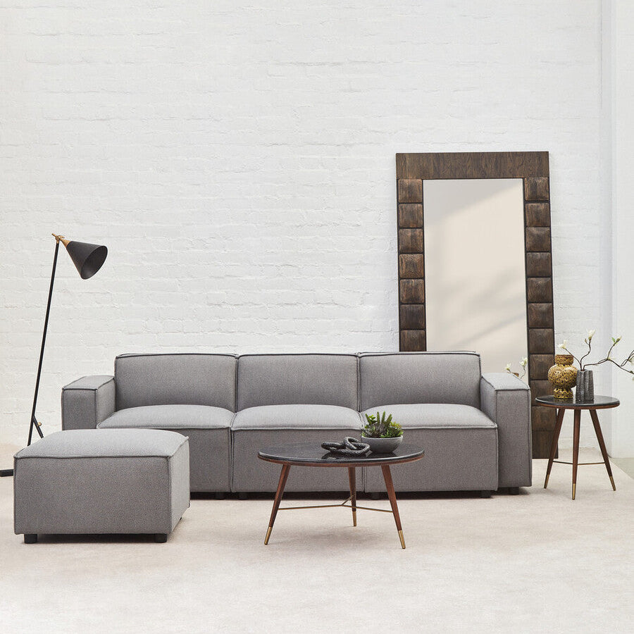 Modern living room with a gray sectional sofa, coffee table, and decorative mirror.