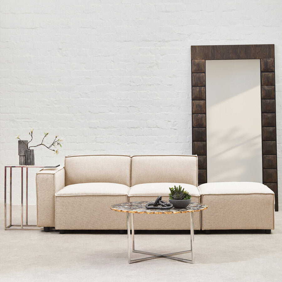 Beige sofa with a coffee table and decorative items against a white brick wall.