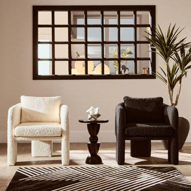 Living room with two armchairs, a small table, and a decorative mirror on the wall.
