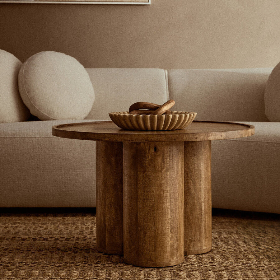 Wooden coffee table with a decorative bowl in front of a beige sofa.
