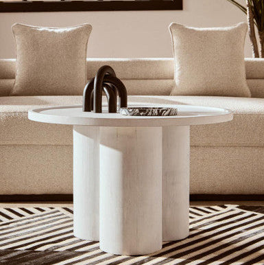 Modern living room with a beige sofa, round marble coffee table, and decorative items.