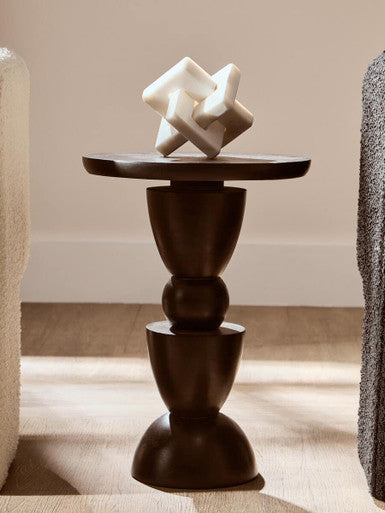 Decorative sculpture on a dark wooden pedestal against a neutral background
