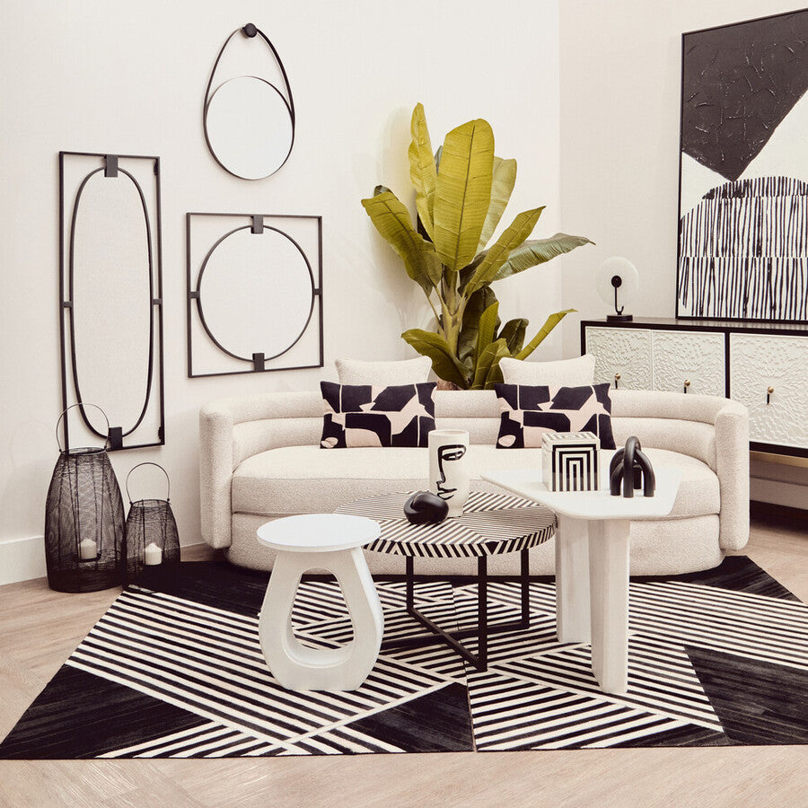 Modern living room with white sofa, black and white decor, and a plant.