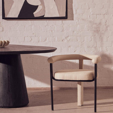 Dining room with a round table and a chair against a light brick wall.