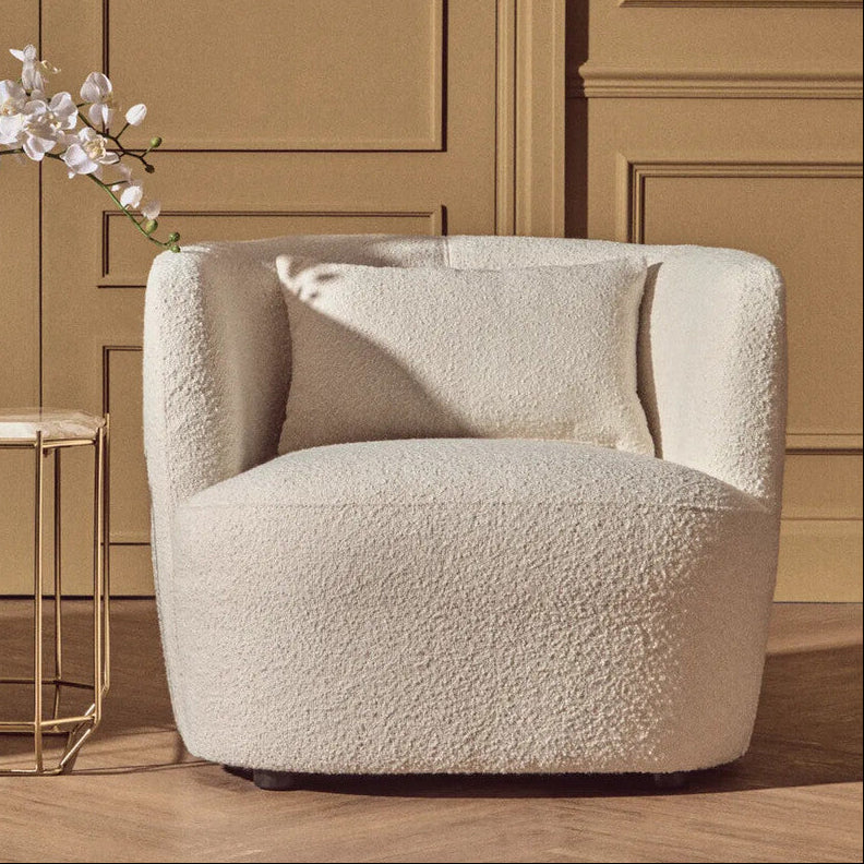 Beige armchair in a room with wooden paneling and a small table with a decorative vase.