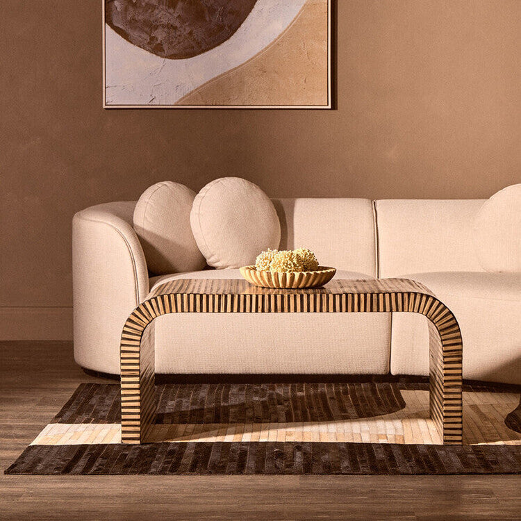 Modern living room with a beige sofa, wooden coffee table, and abstract art on the wall.