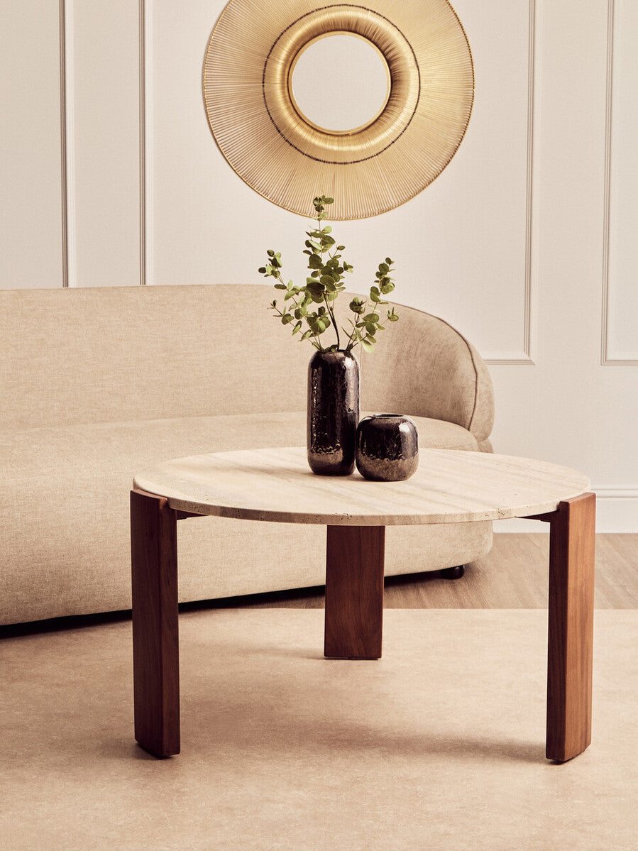 Round coffee table with two vases and a plant in a living room setting.