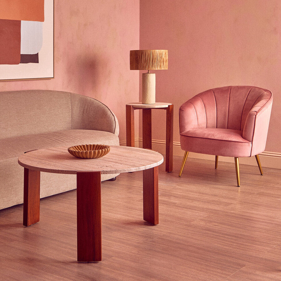 Modern living room with pink walls, a round wooden table, and a pink chair.