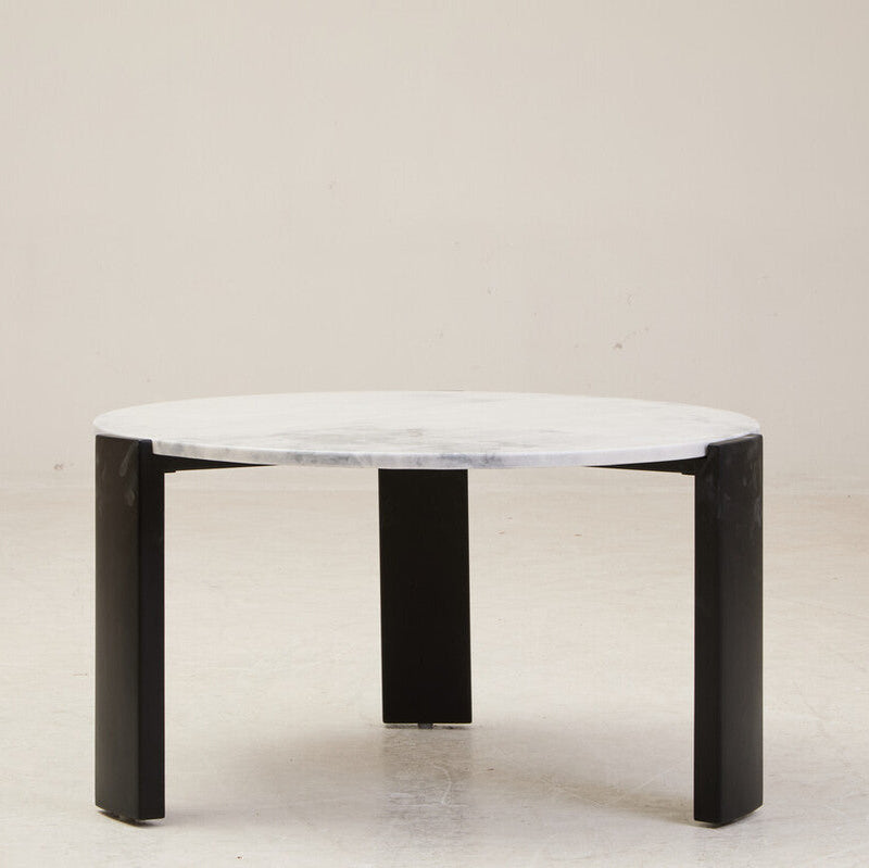 Round marble table with black legs on a plain background