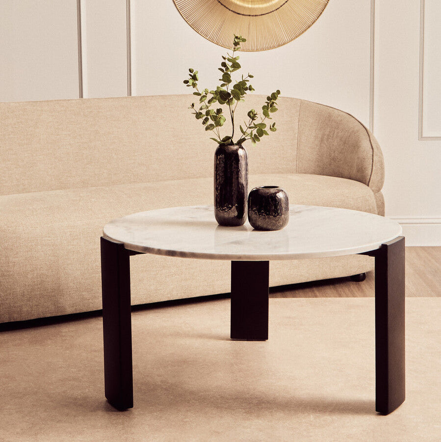 Modern living room with a beige sofa, marble coffee table, and decorative wall art.