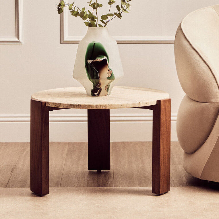 Wooden side table with a vase and plant in a living room setting