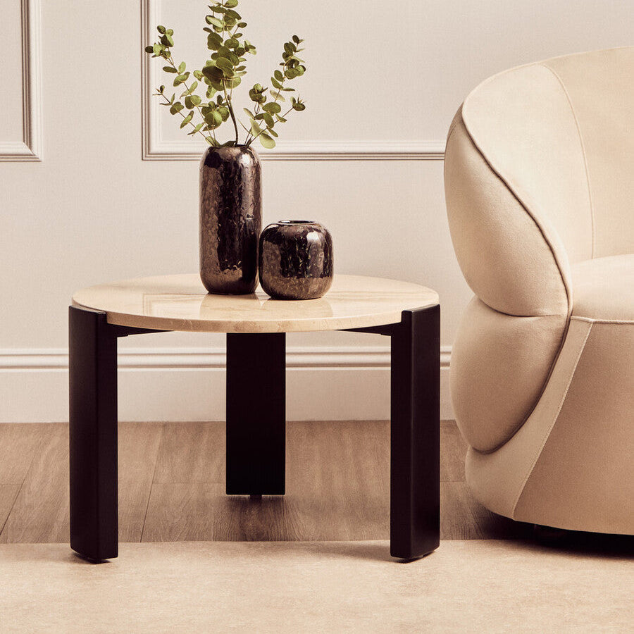 Round wooden side table with two vases and a plant in a living room setting.