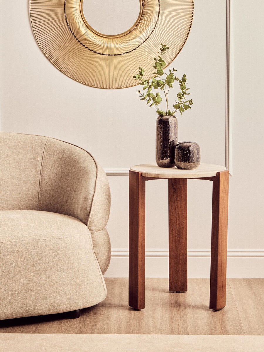 Wooden side table with two vases and a plant next to a beige armchair.