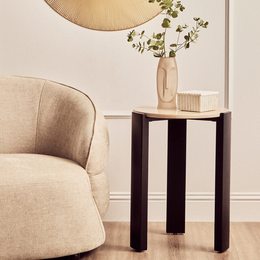Modern living room with a beige armchair, side table, and decorative mirror.