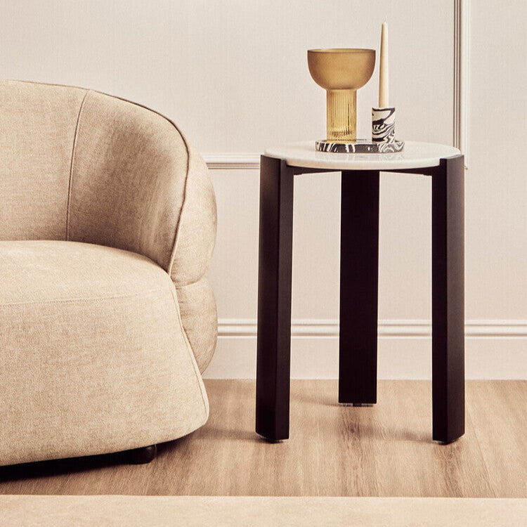 Modern living room with a beige armchair, round mirror, and side table.