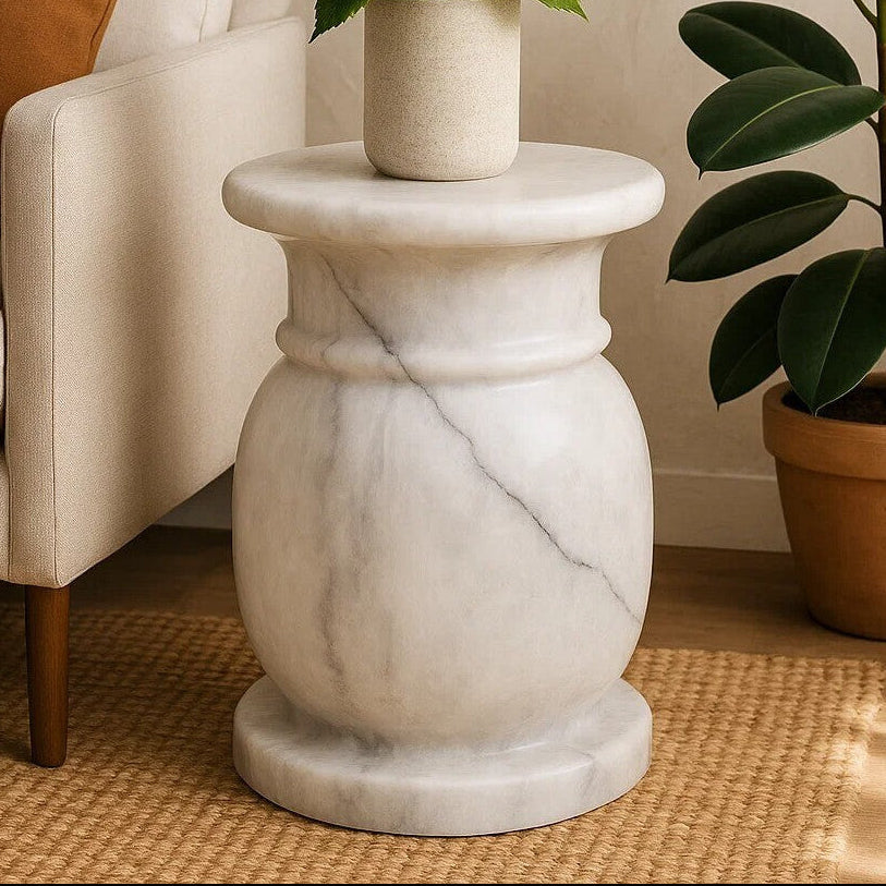 Marble side table with white flowers and a plant in a living room setting