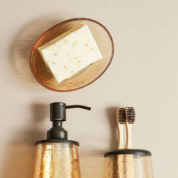 Bathroom accessories including a soap dispenser, toothbrush holder, and soap on a beige wall.