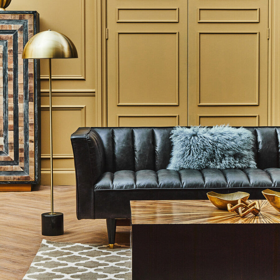 Modern living room with black leather sofa, wooden coffee table, and decorative elements.