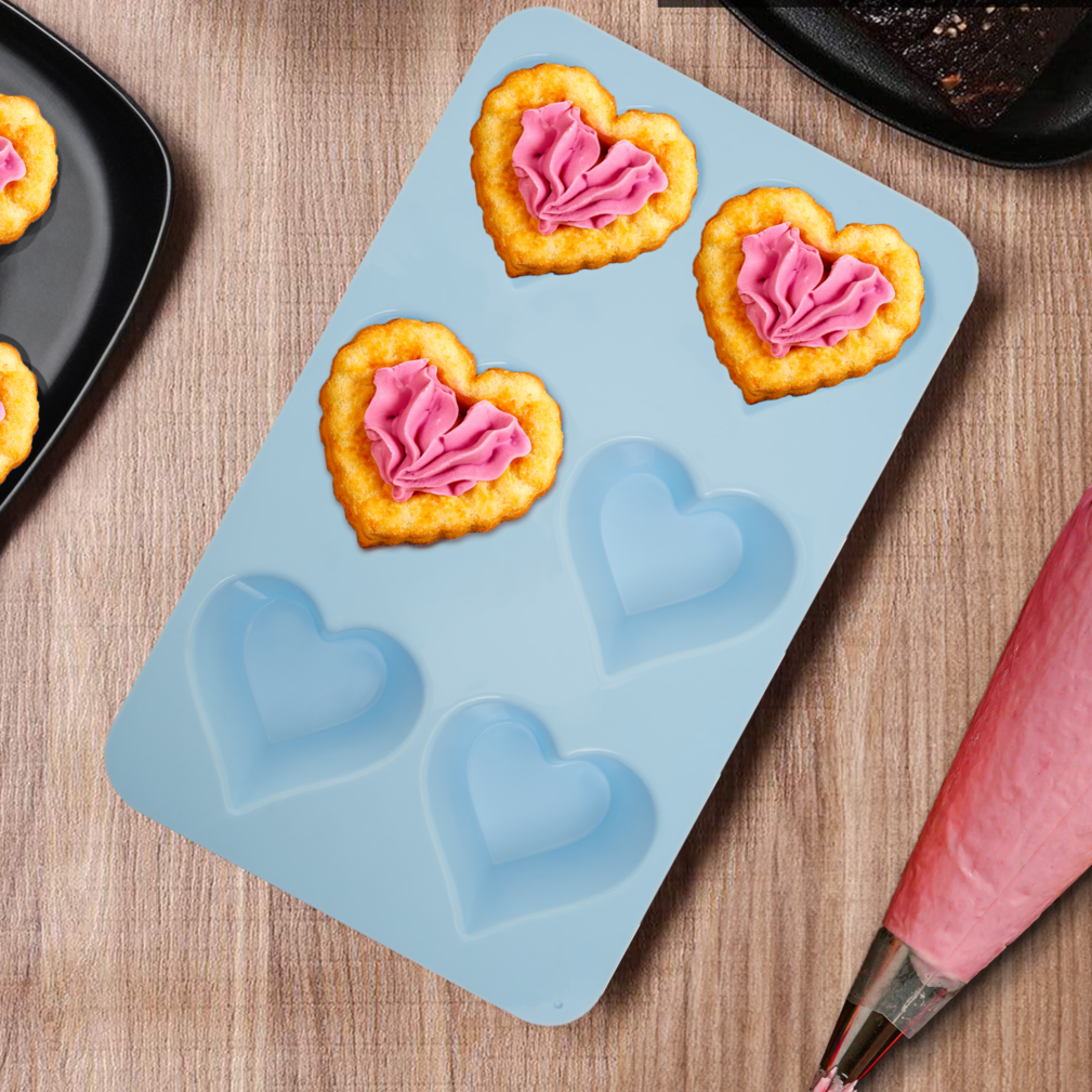 Silicone mold with heart shapes on a wooden surface with baking tools.