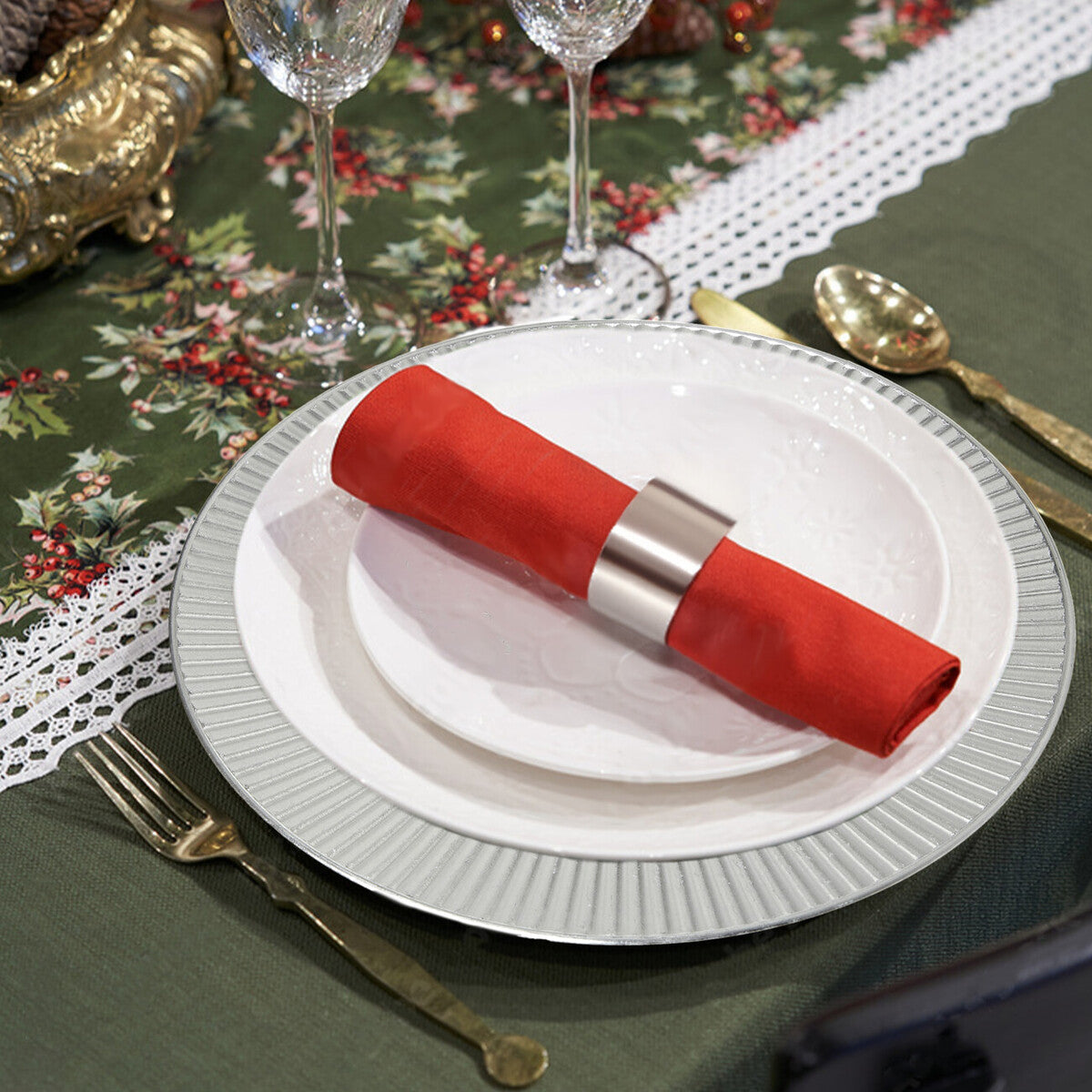 Set table with red napkin, white plates, and silverware on a floral tablecloth.