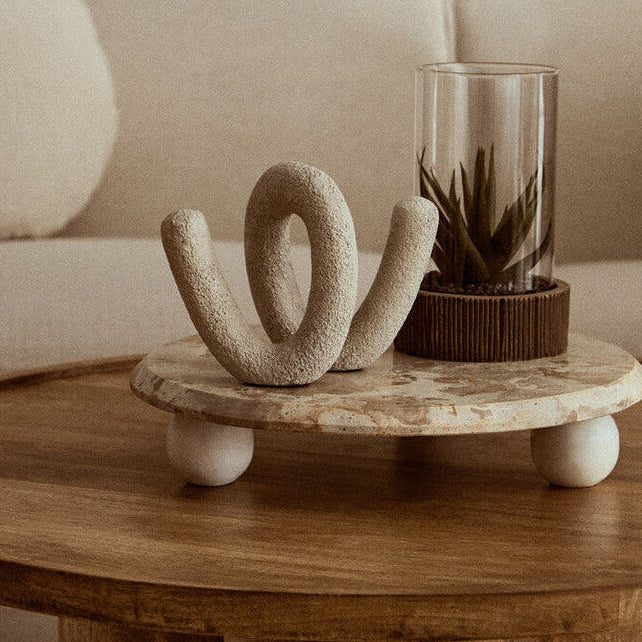 Decorative table with a sculpture and plant in a living room setting