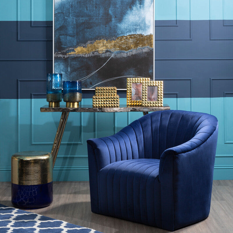 Modern interior with blue armchair, abstract art, and decorative items against a blue wall.