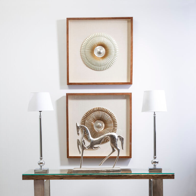 Two framed artworks on a wall above a glass console table with decorative items.
