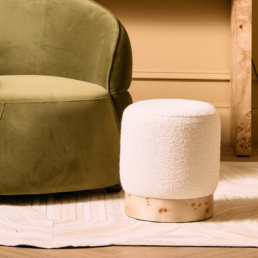 Green armchair with a white textured stool on a wooden floor.