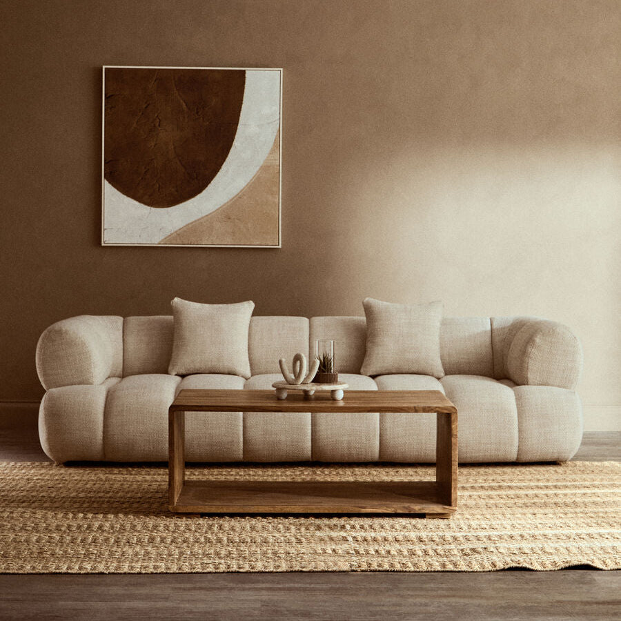 Beige sofa in a living room with a abstract painting on the wall.