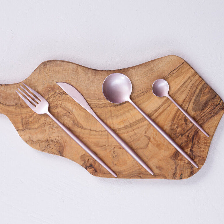 Wooden cutting board with silverware on a light gray background