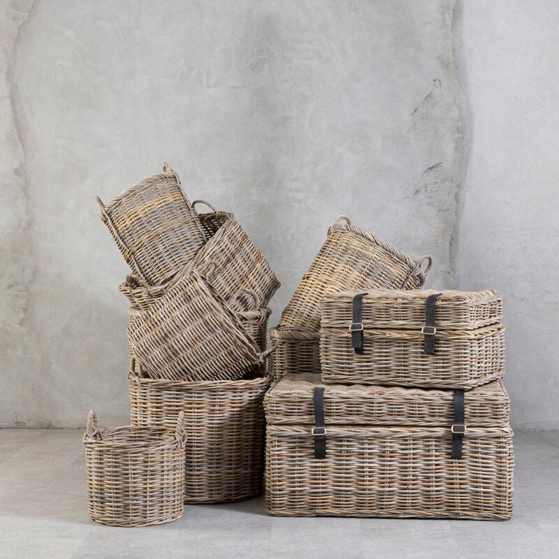 Set of wicker baskets of various sizes against a gray concrete wall.