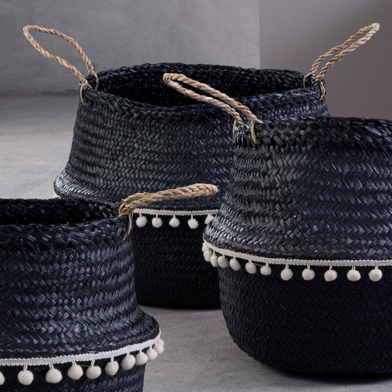 Set of black woven baskets with pom-pom details on a gray background