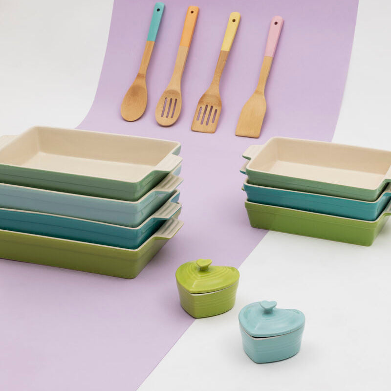 Set of ceramic dishes and kitchen utensils on a two-tone purple and white background