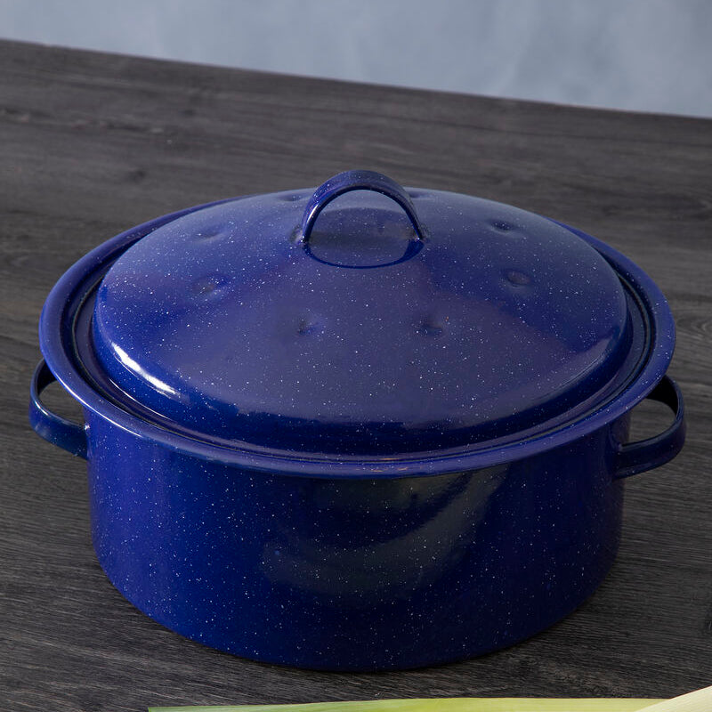 Blue enameled cast iron casserole dish on a wooden surface with leeks.