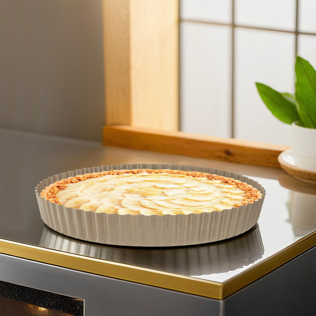 Apple pie in a tart dish on a kitchen counter with a plant in the background