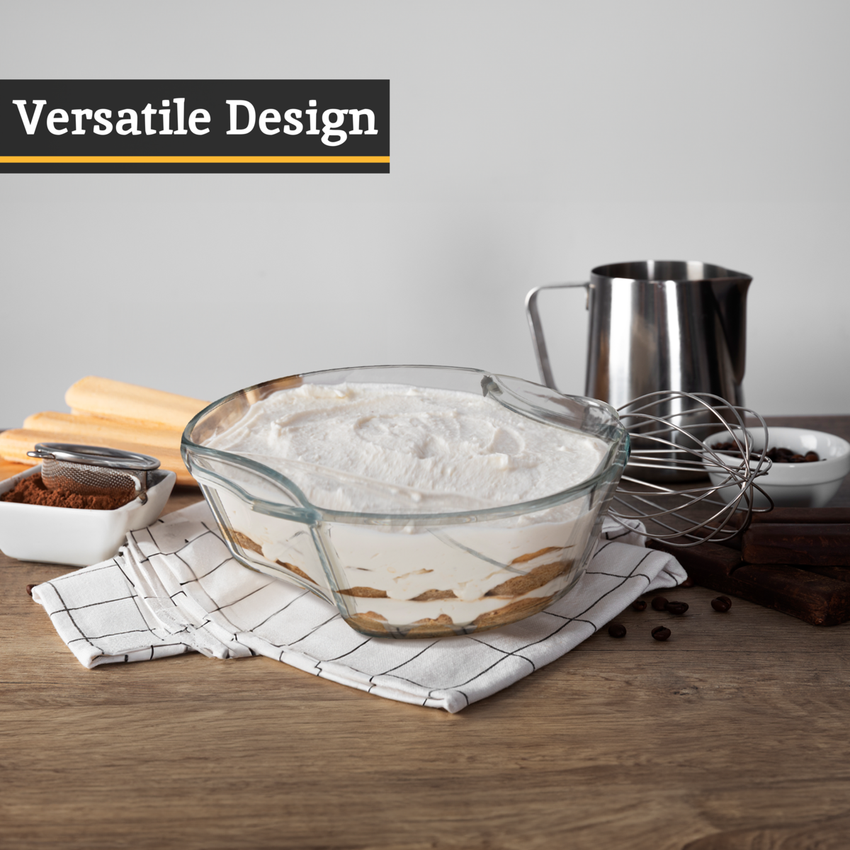 Glass mixing bowl with flour on a wooden table, surrounded by baking ingredients.