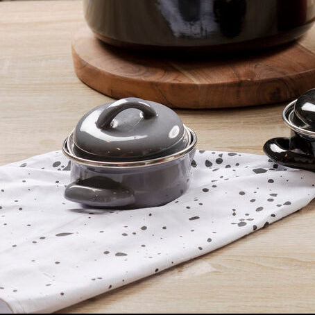 Collection of black, red, and white ceramic cookware on a wooden surface.