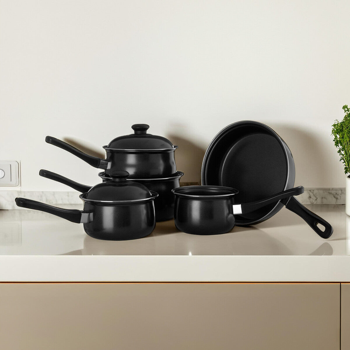 Set of black cookware including pots and a frying pan on a kitchen counter.