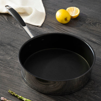 Black frying pan on a wooden surface with lemons and asparagus nearby