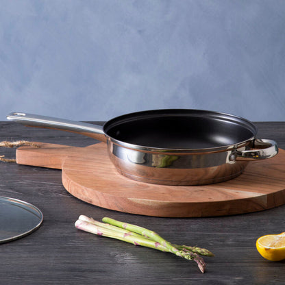 Cooking pan on a wooden cutting board with lemons and asparagus on a dark surface