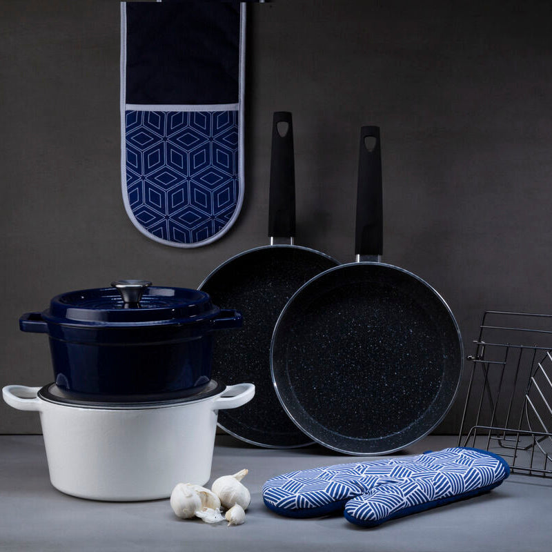 Culinary set with pots, pans, and kitchen tools on a gray surface against a dark background