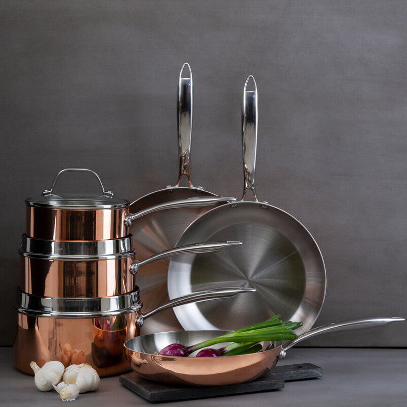 Set of copper cookware with lids on a gray background