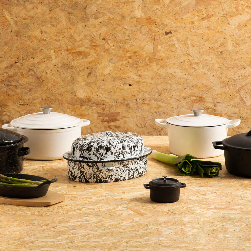Collection of cookware including pots and pans on a wooden surface with a wooden wall background.