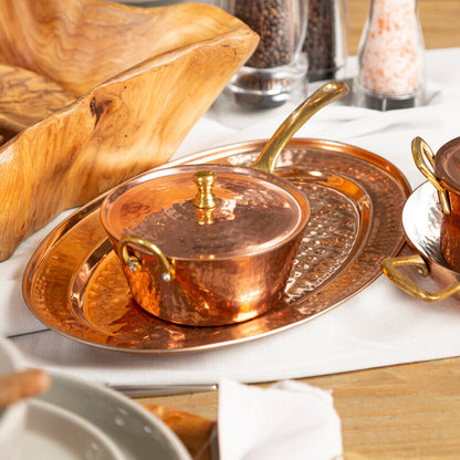 Copper pots and trays on a wooden table with a white cloth