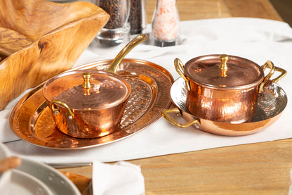 Copper pots and trays on a wooden table with a white cloth